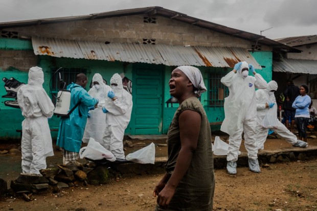 This Sept. 18, 2014, photograph by New York Times photographer Daniel Berehulak, part of a winning series,  provided by Columbia University shows a relative grieving as a Liberian Red Cross burial team dresses in protective clothing before removing the body of a suspected Ebola victim in central Monrovia, Liberia. Berehulak is the winner of the 2015 Pulitzer Prize for Feature Photography, announced Monday, April 20, 2015, at Columbia University in New York. (Daniel Berehulak, New York Times, Columbia University via AP) ORG XMIT: NYR202